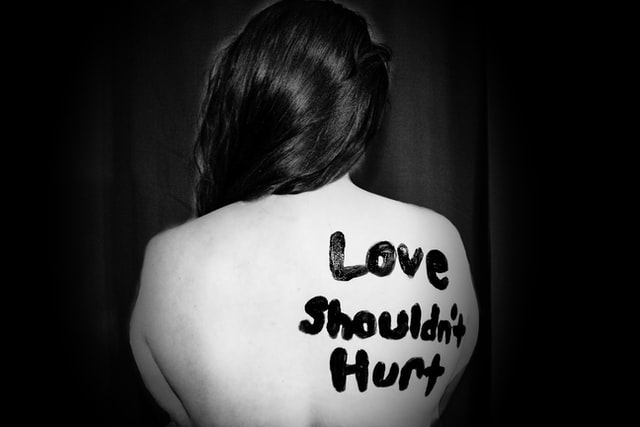 Love should not hurt is written on woman's back referring to domestic abuse